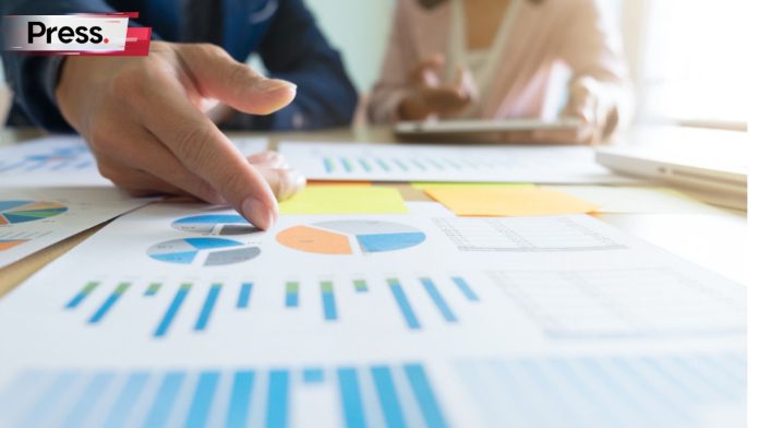 A picture of a man's hand, pointing out something on a chart to a woman whose face we don't see either. They are performing SEO competitor analysis.