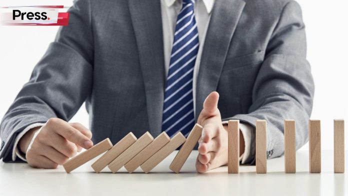 A businessman plays with falling dominos, which represent SME challenges.